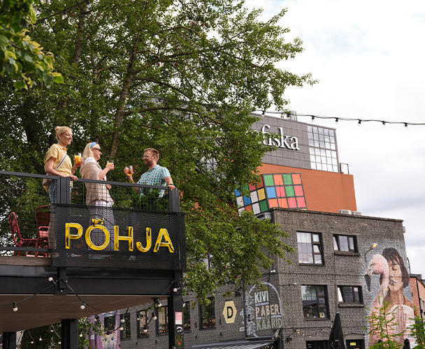 Tre vänner står på en balkong i Telleskivi i Tallinn